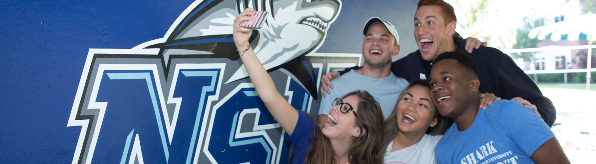 students taking a selfie in front of nsu logo