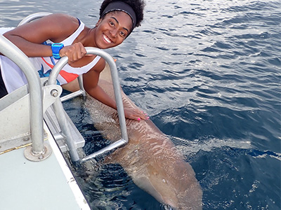 young lady smiling and touching a shark