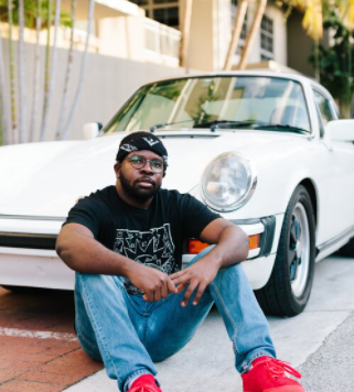 Alonzo Williams seated in front of a classic car 