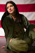 Mariah Busk seated on floor, looking away from camera with American flag in the background
